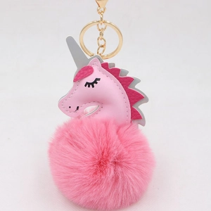 Detailed close-up of pink unicorn keychain with fluffy fur pompom and gold hardware