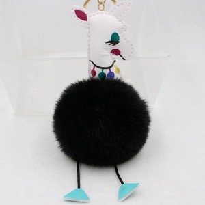 Détail d'un porte-clés girafe à pompon noir avec simili cuir blanc et anneau doré