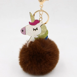 Macro detail of unicorn charm with glitter ears and brown faux fur pom pom keychain