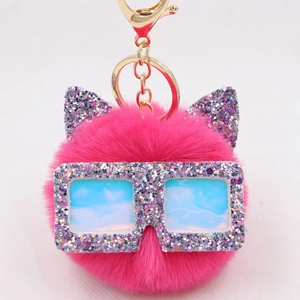 Détail du porte-clés pompon peluche rose rouge avec oreilles de chat et lunettes pailletées