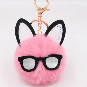 Close-up of pink fluffy bunny pom pom keychain with cute black glasses and gold hardware