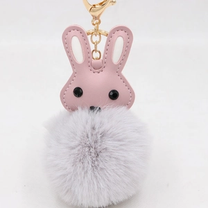 Vue détaillée d'un lapin en cuir PU rose avec pompon gris et porte-clés doré élégant