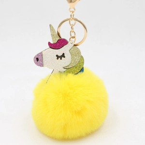 Detail of colorful unicorn keychain with yellow faux fur pompom and golden metal clip