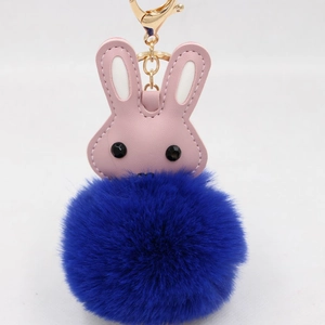 Détail de la tête de lapin en similicuir rose et du pompon bleu marine sur porte-clés doré