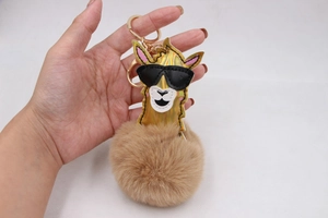 Détail d'un porte-clés alpaga en pompon marron avec lunettes de soleil et crochet doré