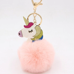 Detail of pink faux fur pompom and glitter unicorn charm on a gold keychain