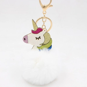 Detailed macro view of white plush pompom unicorn keychain with gold metal lobster clasp