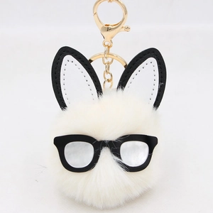 Detail of white plush bunny keychain with long ears and stylish black frame glasses