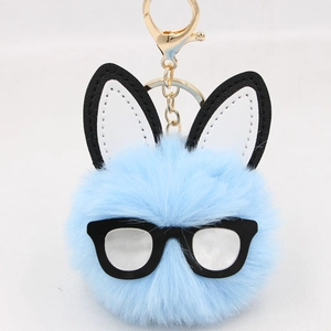 Detail of light blue fluffy bunny keychain with black glasses and gold metal clasp