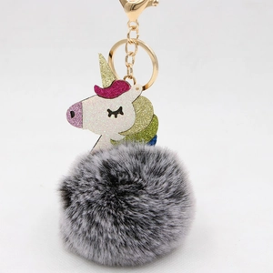 Close-up of fluffy grey faux fur pom pom keychain with glitter unicorn charm detail
