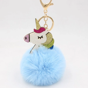 Detail of blue faux fur pompom keychain with a sparkly glitter unicorn and gold lobster clasp