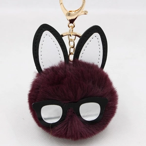 Detailed close-up of a plush bunny keychain with dark purple fur and black-rimmed glasses