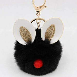 Detail of a fluffy black pompom keychain with festive bunny ears and golden metal hardware