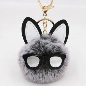 Detailed view of plush rabbit ear keychain with black rim glasses and faux fur ball