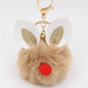 Detail of a brown plush ball keychain with rabbit ears and golden clasp on white background