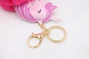 Macro shot of unicorn bag charm featuring pink PU leather, gold hardware, and fuchsia pom-pom