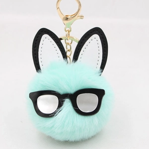 Detail of mint green plush ball keychain with black glasses and bunny ears on white background