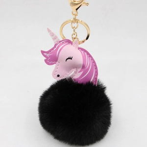 Detailed view of unicorn leather charm with black fluffy pom-pom and gold keychain hook