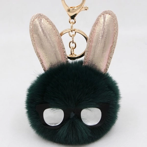 Détail d'un porte-clés lapin en fausse fourrure vert foncé avec oreilles dorées brillantes