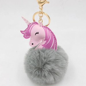 Detail of pink faux leather unicorn charm with gray fluffy pom pom and gold keychain