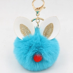 Detail of blue faux fur rabbit keychain with gold glitter ears and a red pompom nose