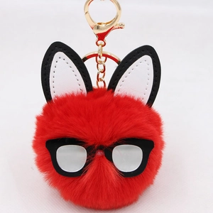 Macro view of a red fluffy pompom keychain featuring long ears and black glasses frame