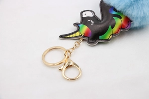 Detailed macro view of black leather unicorn charm with blue fluffy pompom and gold ring