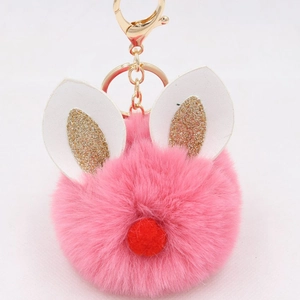Macro shot of pink faux fur pompom keychain with gold glitter bunny ears and metal clasp