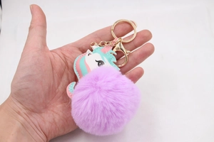 Close-up of fluffy purple faux fur unicorn keychain with gold spring clasp and pastel charm