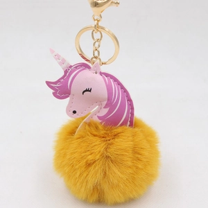 Detail of yellow unicorn faux fur pompom keychain with golden metal clasp and ring