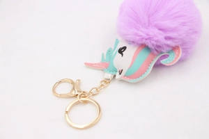 Close-up of purple faux fur pompom keychain with cartoon unicorn patch and gold hardware