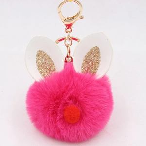 Close-up of rose red plush pompom keychain with golden rabbit ears and lobster clasp