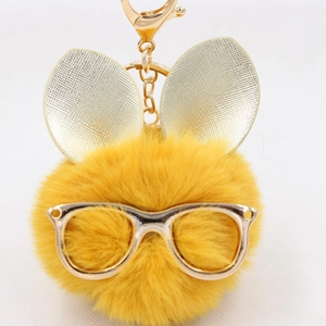 Gros plan du porte-clés pompon en fausse fourrure jaune avec lunettes et oreilles