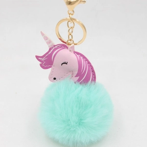 Detailed macro view of mint green plush fur ball and pink leather unicorn keychain charm