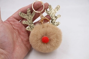 Detailed macro view of a Christmas reindeer plush keychain with gold sequin antlers and a soft fur ball