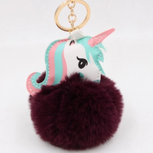 Close-up of fluffy faux fur unicorn keychain with gold metal ring and colorful leather detail