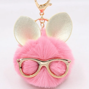 Détail d'un porte-clés pompon rose avec oreilles de lapin dorées et lunettes