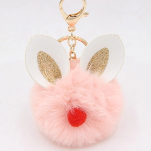 Close-up of pink fur ball keychain with white rabbit ears and golden metal ring