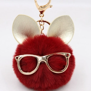 Gros plan d'un porte-clés lapin en peluche rouge foncé avec lunettes et oreilles dorées