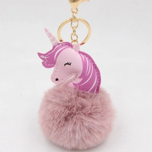 Detail of pink unicorn faux fur pompom keychain with golden metal clasp and ring