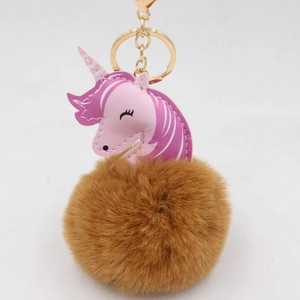 Detail of unicorn plush keychain with pink PU leather patch and fluffy brown pom pom ball