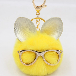 Détail du porte-clés en peluche jaune avec lunettes dorées et oreilles de lapin en métal