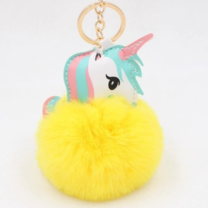 Detail of cute unicorn keychain with soft yellow faux fur pom pom and gold metal ring
