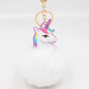 Detailaufnahme von flauschigem Plüsch-Pompon und goldenem Einhorn-Schlüsselanhänger