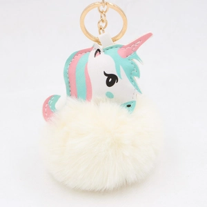 Close-up of golden keychain ring and white fluffy faux fur ball with unicorn charm