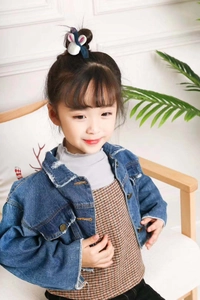 Détail d'un enfant portant une veste en jean bleu foncé et un accessoire en peluche