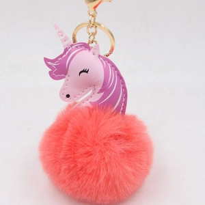 Detail of unicorn plush keychain showing pink PU leather head and fluffy coral fur ball