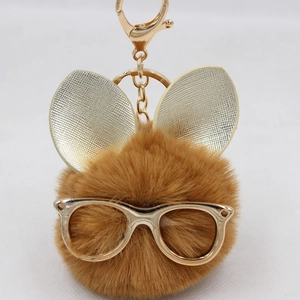 Détail d'un porte-clés pompon créatif avec oreilles de lapin et lunettes dorées