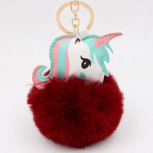Close-up of fluffy burgundy faux fur pompom with white unicorn leather bag charm