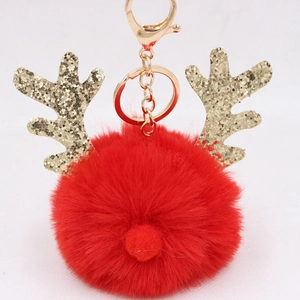 Detail of red plush ball keychain with golden glitter reindeer antlers and metal clasp